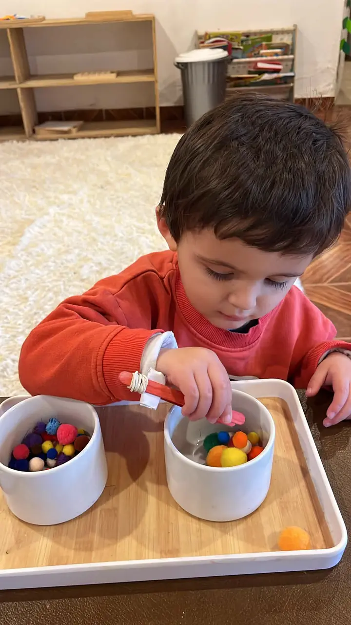 Niño trasladando pompones de un pocillo a otro
